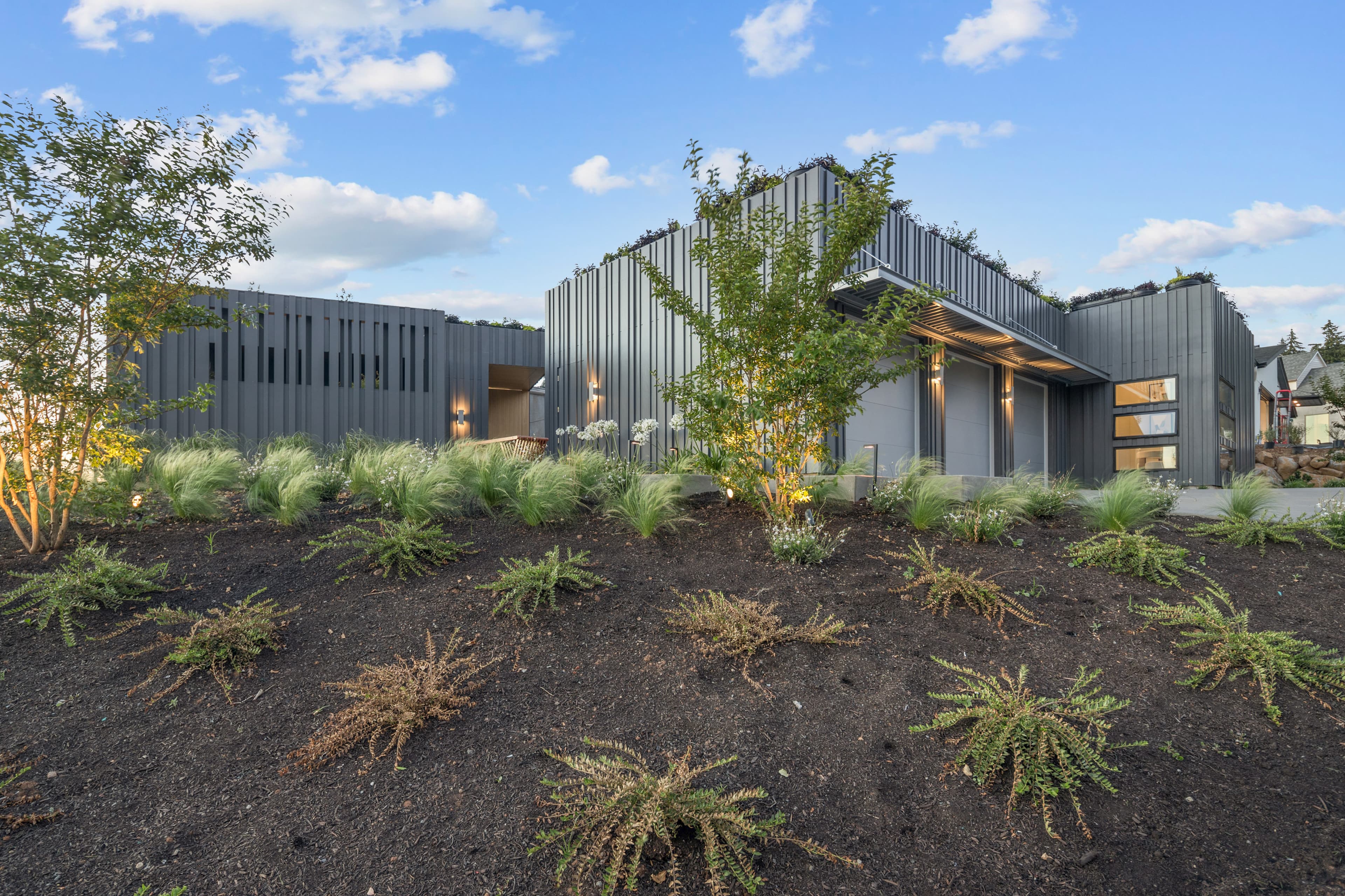 The Creekside Homes 2026 Street of Dreams home — a low, horizontal design with dark vertical batten siding and a living roof
